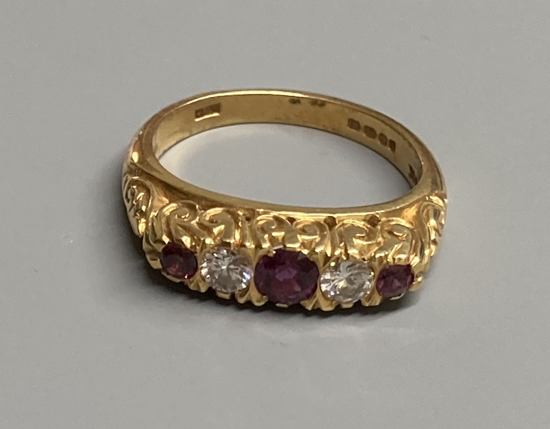 A modern Victorian style 18ct gold, three stone ruby and two diamond set half hoop ring, size N, gross 6.2 grams.